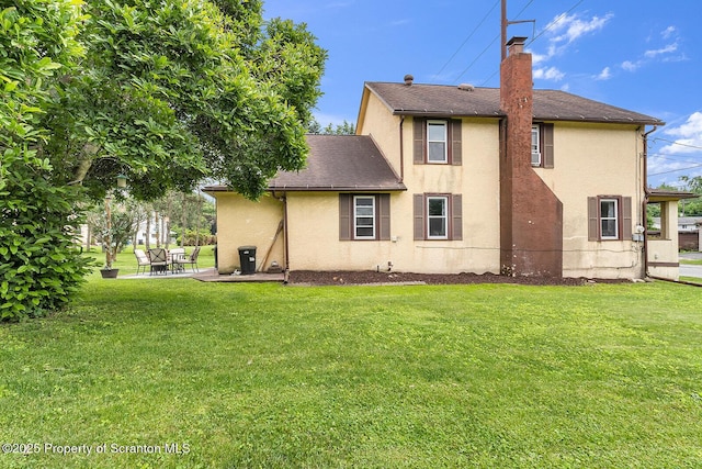 50 Humphrey St Unit 50-51, Old Forge, PA 18518 - back of property with stucco siding, a lawn, a chimney, and a patio area