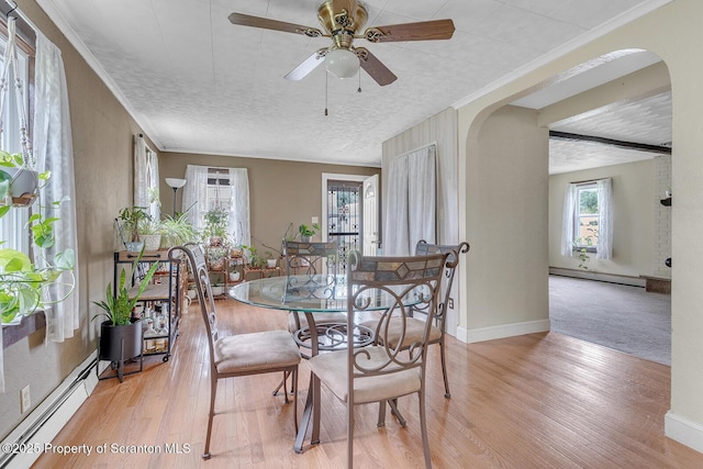 50 Humphrey St Unit 50-51, Old Forge, PA 18518 - dining room featuring baseboard heating, a baseboard heating unit, arched walkways, light wood finished floors, and crown molding