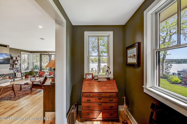 interior space with hardwood / wood-style floors, a water view, and a healthy amount of sunlight