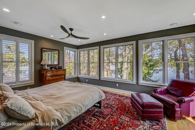 bedroom with ceiling fan, light hardwood / wood-style flooring, and multiple windows