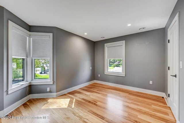 empty room with plenty of natural light and light hardwood / wood-style floors