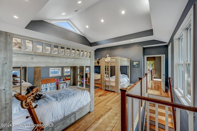 bedroom with hardwood / wood-style floors, high vaulted ceiling, and multiple windows