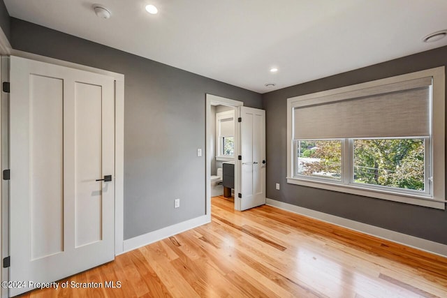 unfurnished bedroom with light hardwood / wood-style flooring and ensuite bath