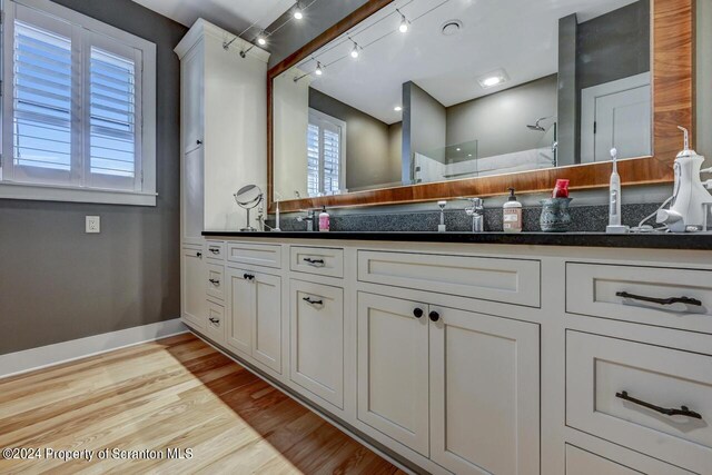 bathroom featuring vanity, wood-type flooring, and walk in shower