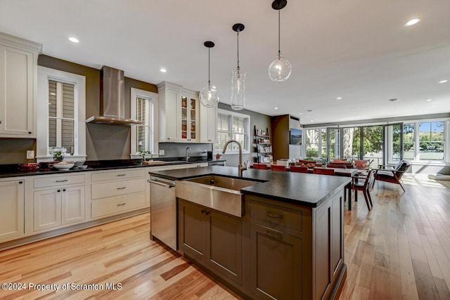 kitchen featuring white cabinetry, stainless steel dishwasher, a kitchen island with sink, and wall chimney exhaust hood