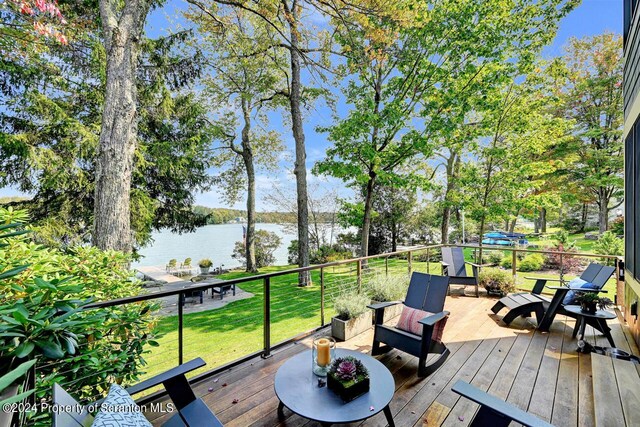 deck with a water view and a lawn