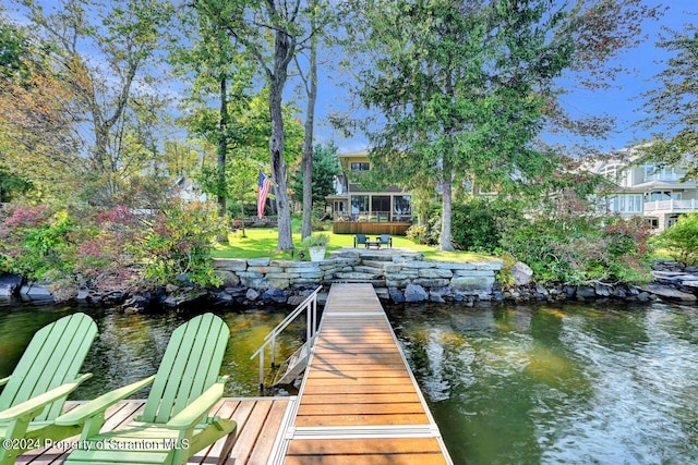 view of dock with a yard and a water view