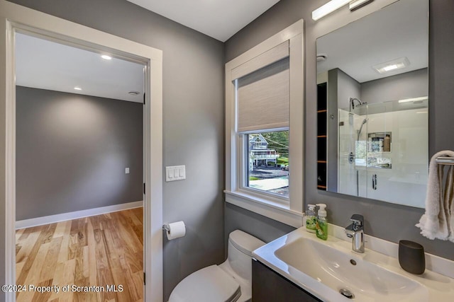 bathroom with a shower with door, vanity, wood-type flooring, and toilet