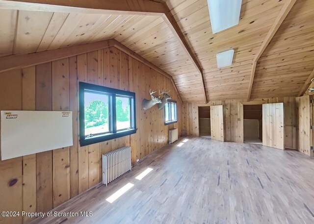 bonus room featuring radiator heating unit, wooden ceiling, vaulted ceiling with beams, hardwood / wood-style floors, and wooden walls