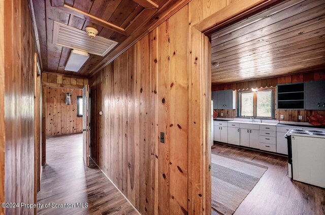 corridor with hardwood / wood-style floors, wood walls, and wood ceiling