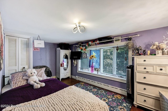 bedroom with dark hardwood / wood-style floors, baseboard heating, and a closet