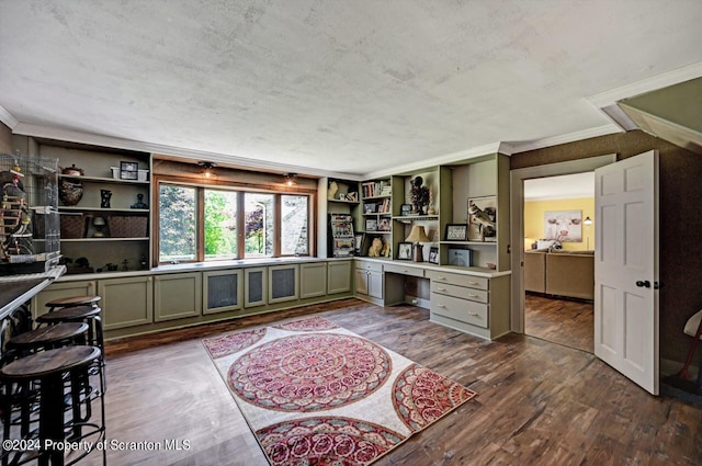 home office with ornamental molding, built in desk, and dark wood-type flooring