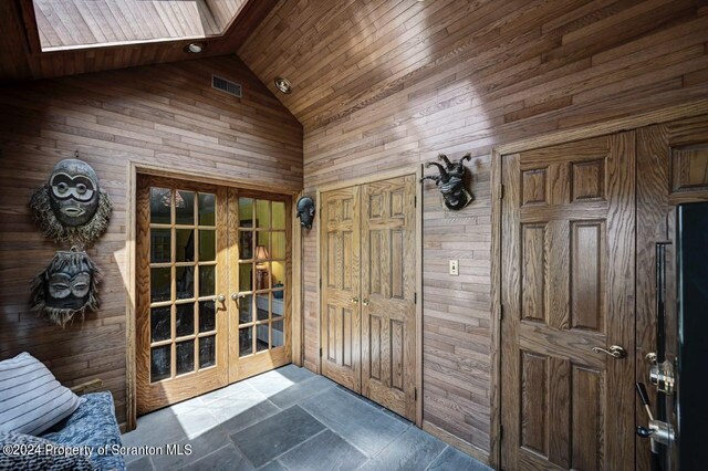 doorway featuring lofted ceiling with skylight, wooden walls, and wood ceiling