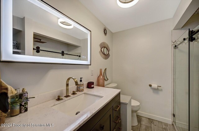 bathroom featuring vanity, an enclosed shower, and toilet