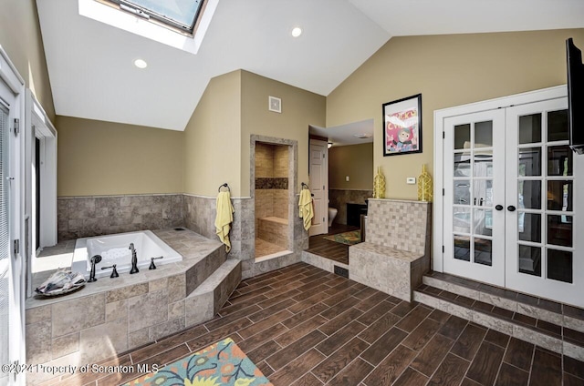 bathroom with french doors, independent shower and bath, and vaulted ceiling with skylight