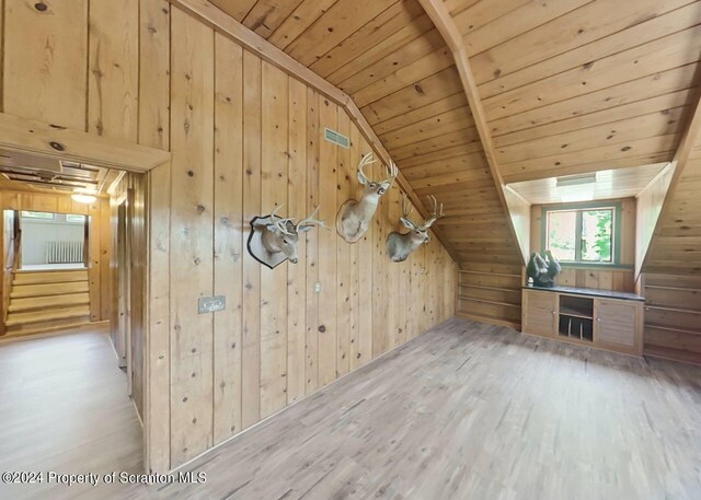 additional living space with light hardwood / wood-style floors, vaulted ceiling, wood ceiling, and wood walls