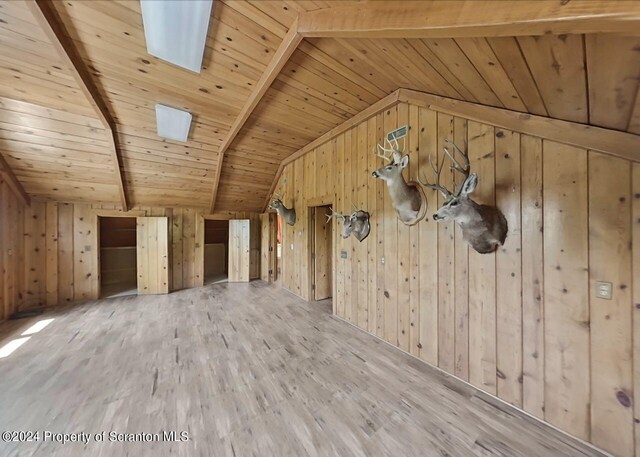 bonus room featuring lofted ceiling with skylight, wood ceiling, wood walls, and wood-type flooring