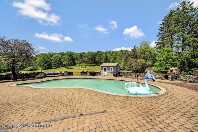 view of pool with a patio area and an outbuilding