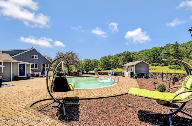 view of swimming pool featuring a patio, pool water feature, and an outdoor structure