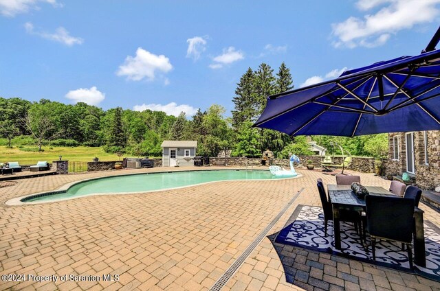 view of swimming pool with pool water feature, an outbuilding, and a patio