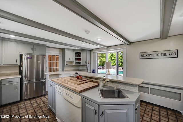 kitchen featuring stainless steel refrigerator, dishwasher, sink, gray cabinets, and a kitchen island with sink