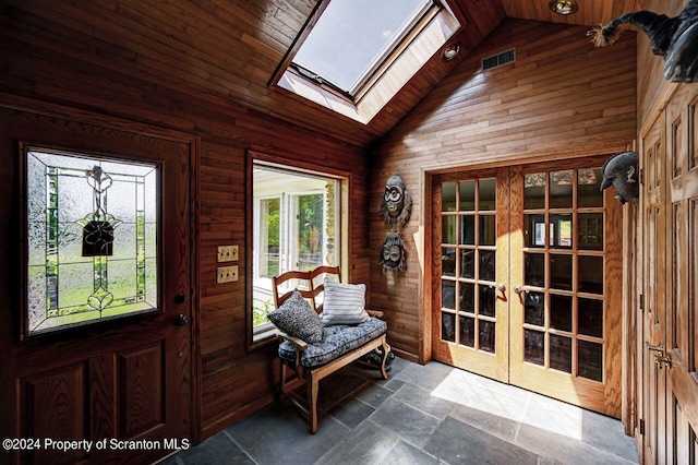 entrance foyer featuring vaulted ceiling with skylight, wood walls, wood ceiling, and french doors