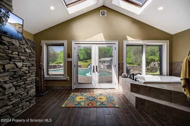 doorway to outside featuring vaulted ceiling with skylight, a wealth of natural light, and french doors