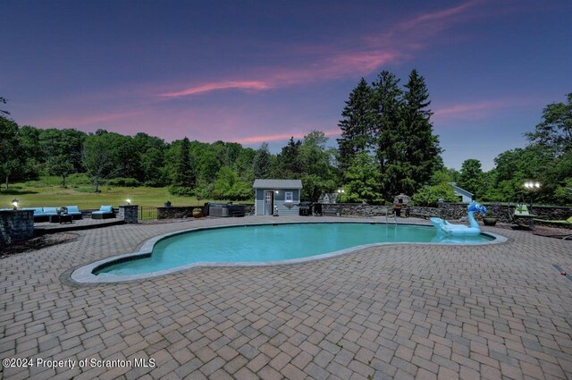 pool at dusk with an outbuilding and a patio