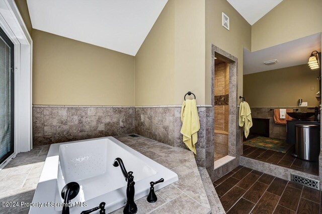 bathroom with a tub to relax in and vaulted ceiling