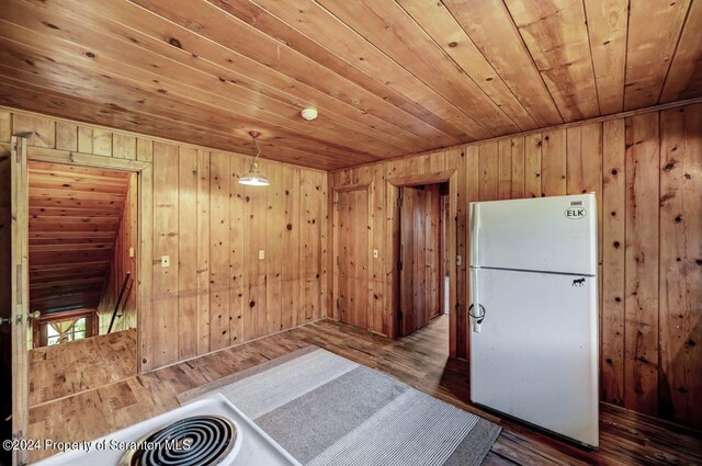 kitchen featuring hanging light fixtures, wooden ceiling, wood walls, hardwood / wood-style floors, and white fridge