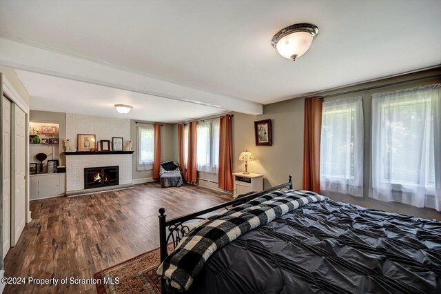 bedroom featuring hardwood / wood-style flooring and a brick fireplace