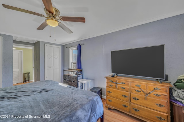 bedroom featuring ceiling fan, a closet, crown molding, and light hardwood / wood-style flooring