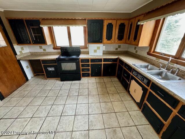 kitchen with light tile patterned floors, black electric range oven, plenty of natural light, and sink