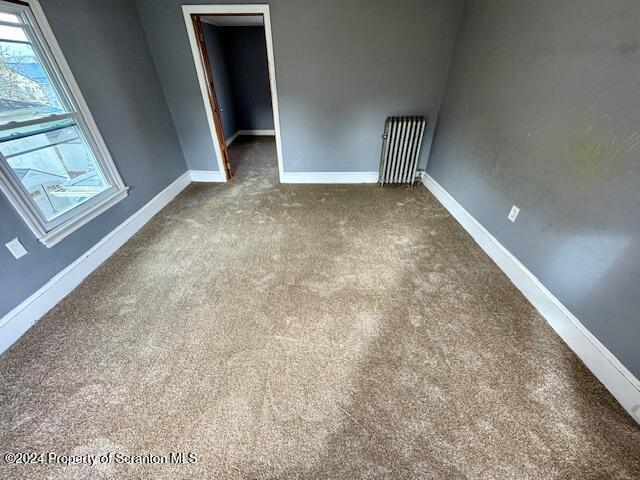 empty room featuring carpet floors and radiator