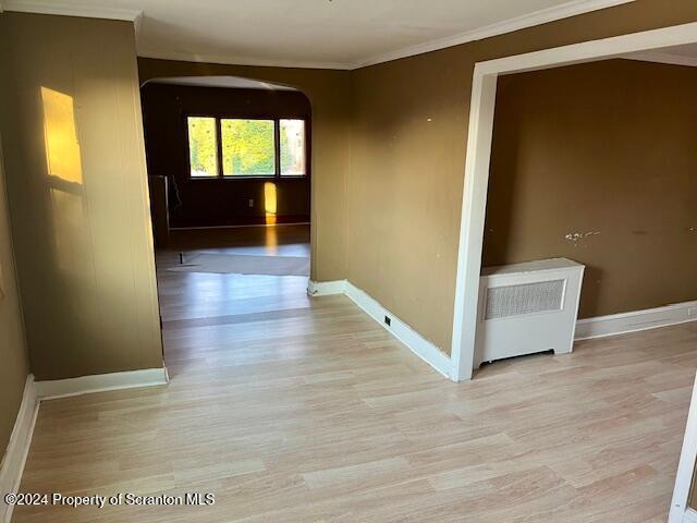 hall with light wood-type flooring and ornamental molding