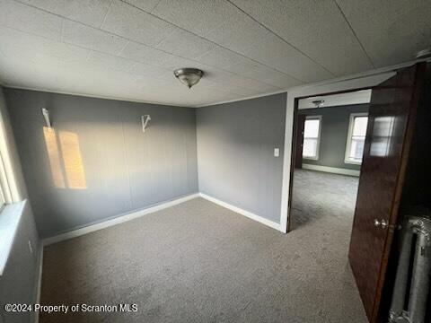 spare room featuring radiator and carpet floors