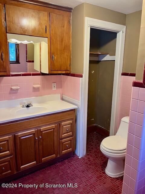 bathroom with vanity, toilet, and tile walls