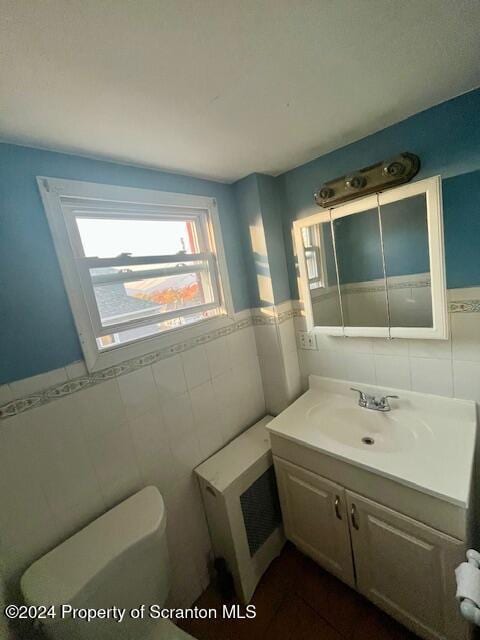 bathroom with vanity, toilet, and tile walls