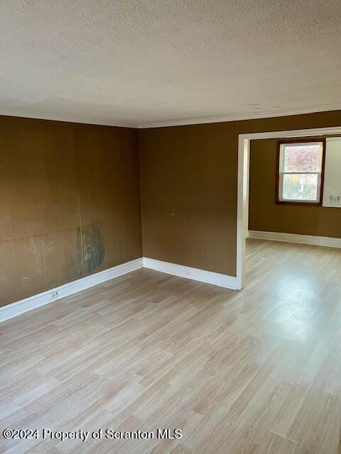 empty room with light hardwood / wood-style floors and a textured ceiling