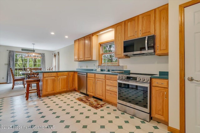 86 Paupack Point Rd, Hawley, PA 18428 - kitchen with appliances with stainless steel finishes, a peninsula, dark countertops, recessed lighting, and hanging light fixtures