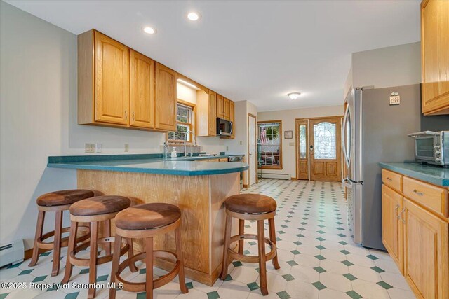 86 Paupack Point Rd, Hawley, PA 18428 - kitchen with light flooring, a kitchen breakfast bar, a baseboard heating unit, stainless steel appliances, and a peninsula