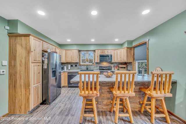 kitchen featuring backsplash, sink, light wood-type flooring, light brown cabinetry, and stainless steel appliances