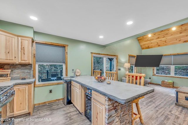 kitchen featuring decorative backsplash, light brown cabinetry, light wood-type flooring, and range