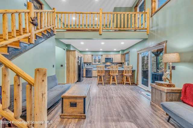 living room with a towering ceiling and light hardwood / wood-style flooring