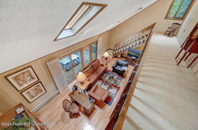 living room with wooden walls, plenty of natural light, and vaulted ceiling with skylight