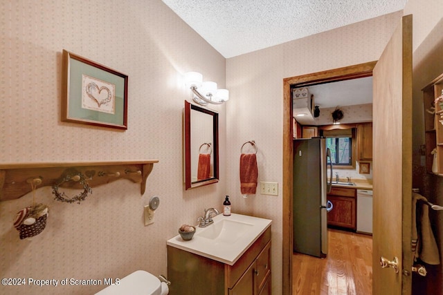 bathroom with hardwood / wood-style floors, vanity, a textured ceiling, and toilet