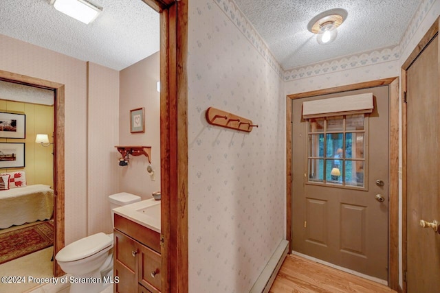 interior space with a textured ceiling, light hardwood / wood-style flooring, and a baseboard heating unit