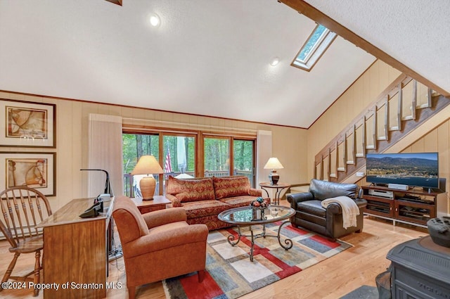 living room featuring vaulted ceiling with skylight, a textured ceiling, and light wood-type flooring