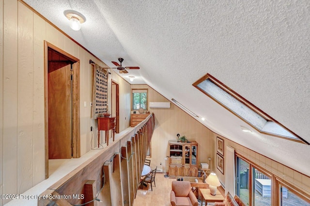 hall with wooden walls and vaulted ceiling with skylight