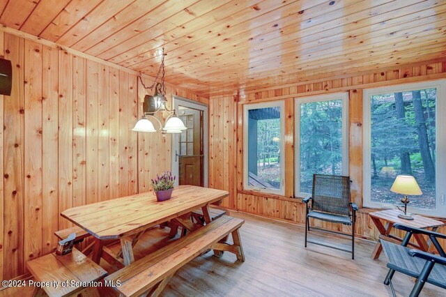 dining space featuring wooden walls, light hardwood / wood-style flooring, and wood ceiling